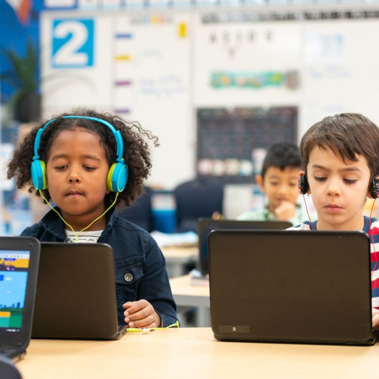 Mvation is a value added reseller for IT solutions to the Education industry; photo of kids with laptops and headphones in classroom.